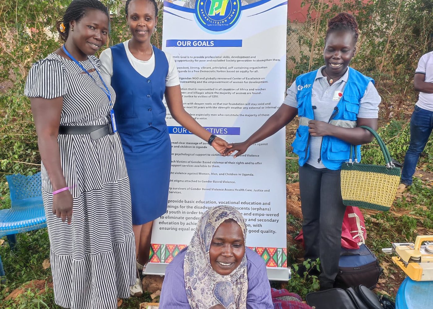 PhiphyMak staff and community members standing together beside an organisation banner during a field visit