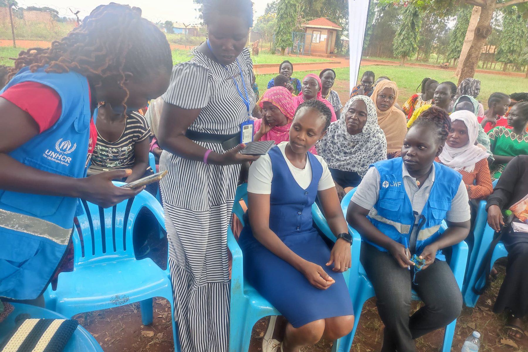 PhiphyMak team members seated with women and children during a community outreach in Kampala