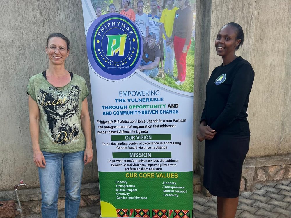Jennifer standing with a PhiphyMak team member beside the organisation banner during her visit from Germany