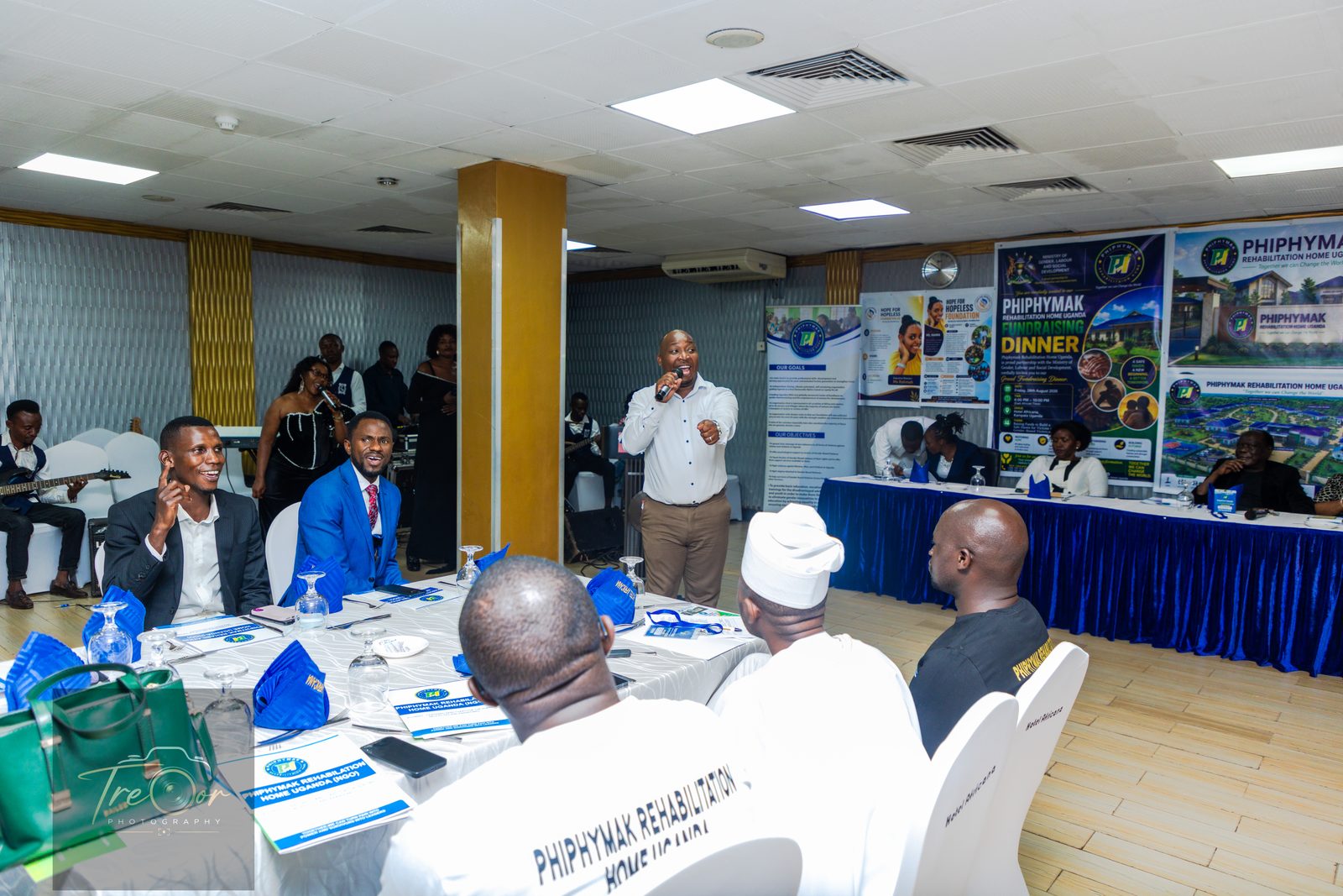 A speaker addressing guests across the dinner tables